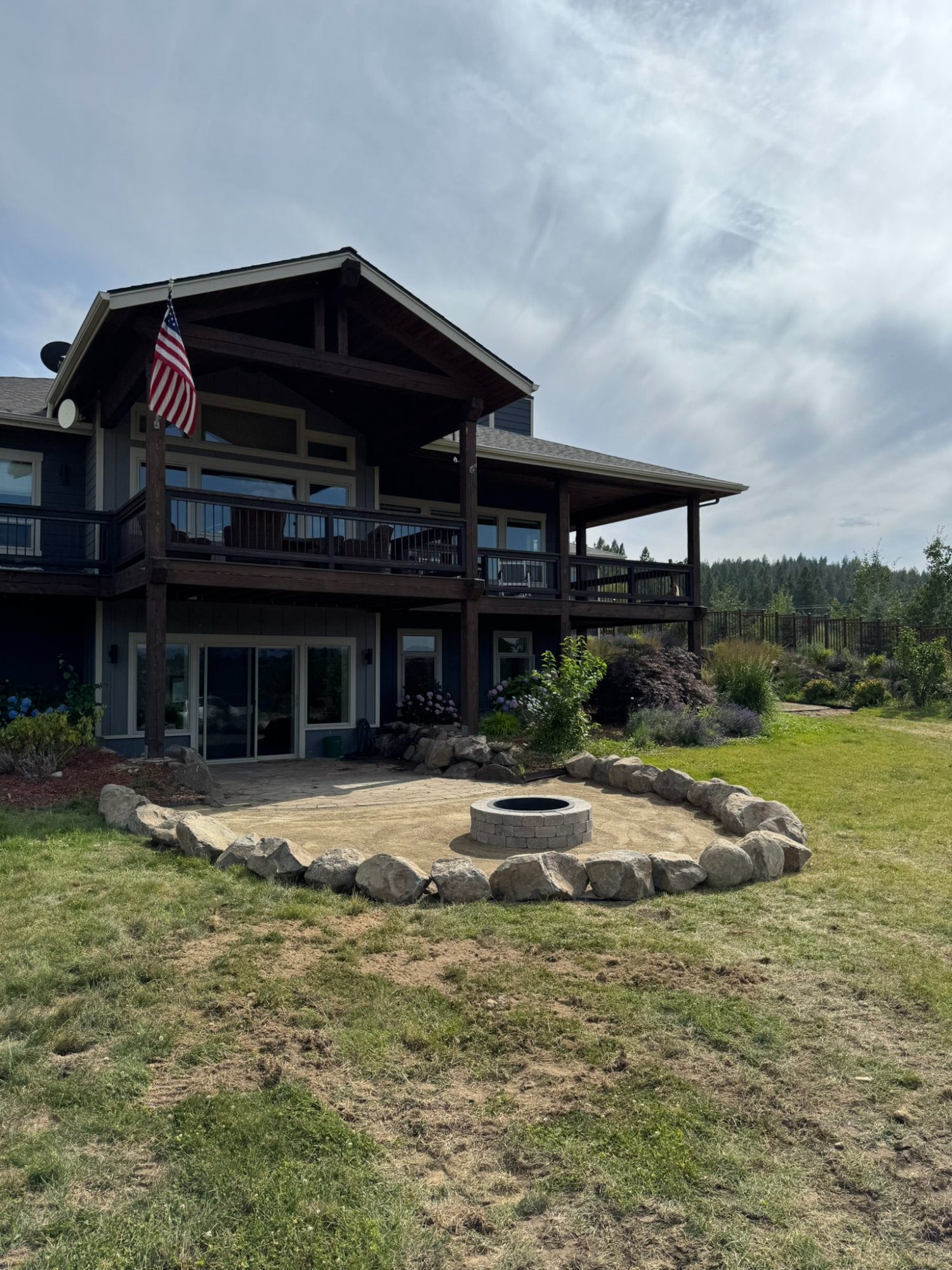 Finished outdoor fire pit patio with rock border at residential property in North Idaho by Elkry Construction