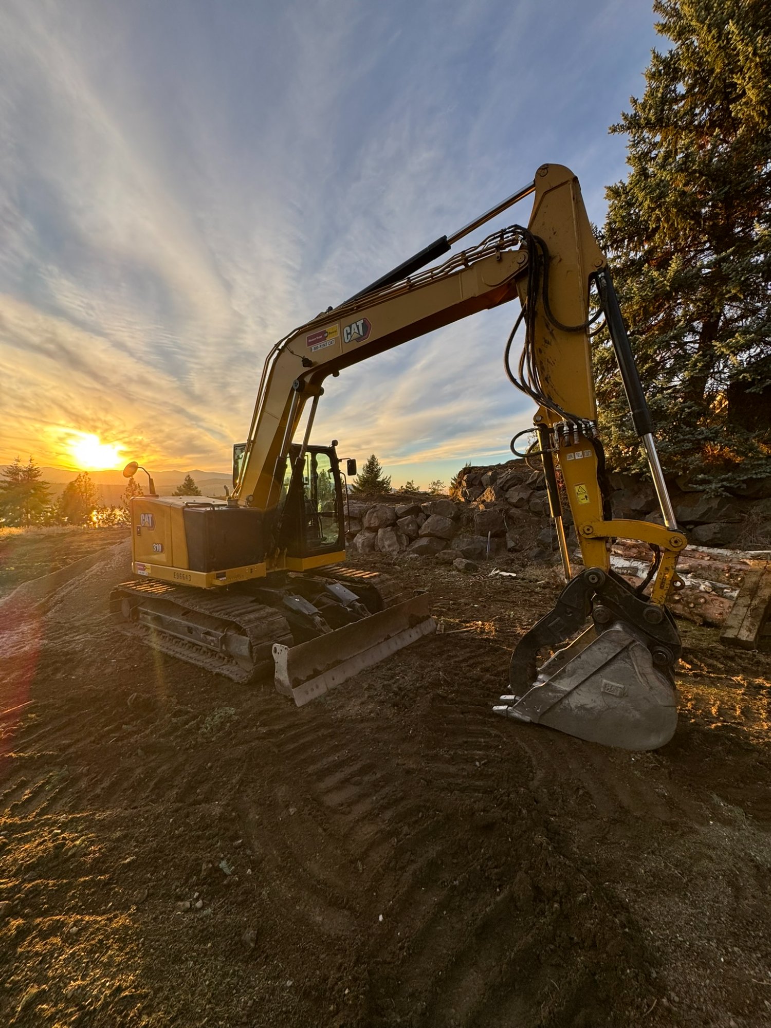 Elkry Construction CAT excavator at sunset on a North Idaho job site